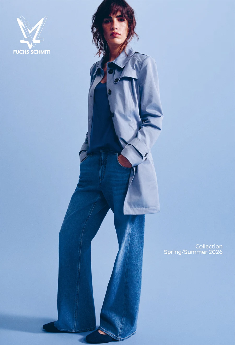 Frau mit Jeans und blauer Jacke vor blauem Hintergrund